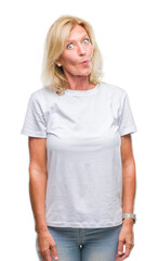 Fototapeta premium Middle age blonde woman over isolated background making fish face with lips, crazy and comical gesture. Funny expression.