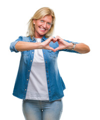 Middle age blonde woman over isolated background smiling in love showing heart symbol and shape with hands. Romantic concept.
