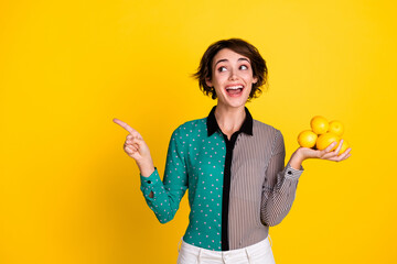 Photo of charming lovely glad woman wear stylish clothes hold lemon look empty space isolated on yellow color background