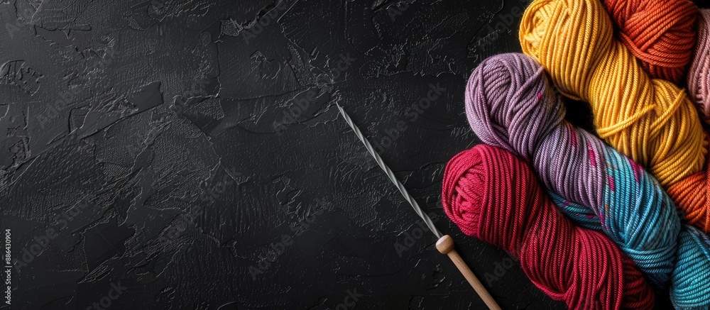 Poster colorful knitting threads and a crochet hook are arranged on a black table leaving room for text nea