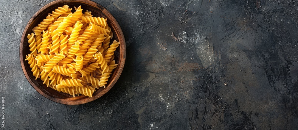 Poster Top view of uncooked Creste di Gallo pasta presented in a wooden bowl on a dark vintage backdrop with room for text or other graphics in the image. with copy space image