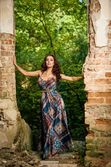 portrait of a beautiful woman in a dress at the ruins of a castle.