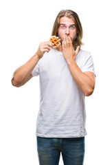 Young handsome man with long hair over isolated background eating waffle cover mouth with hand shocked with shame for mistake, expression of fear, scared in silence, secret concept