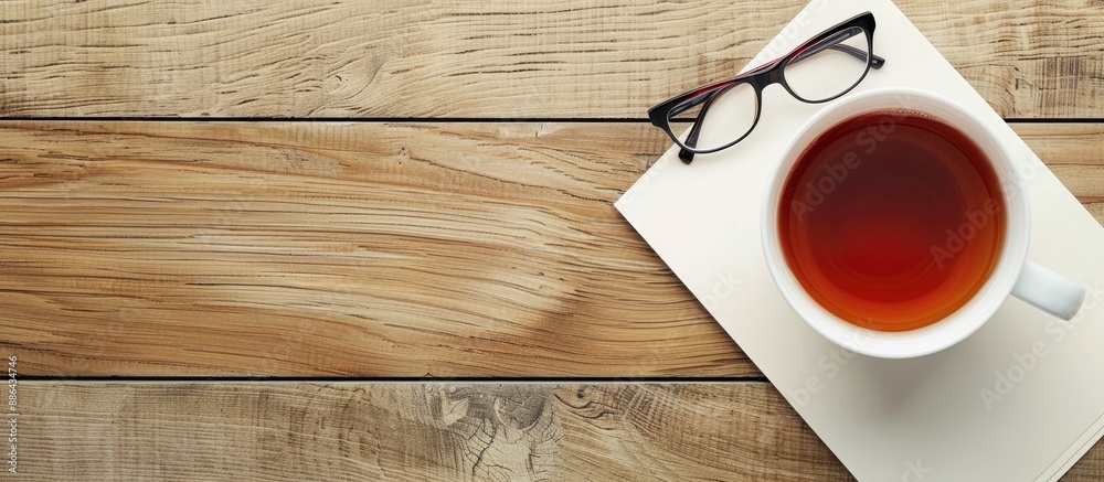 Poster a paper note with eyeglasses and a white cup of tea on a wooden table with a blank copy space image
