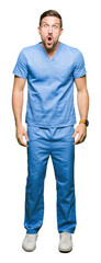 Fototapeta premium Handsome doctor man wearing medical uniform over isolated background afraid and shocked with surprise expression, fear and excited face.