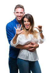 Young couple in love over isolated background showing and pointing up with fingers number six while smiling confident and happy.