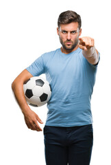 Young handsome man holding soccer football ball over isolated background pointing with finger to the camera and to you, hand sign, positive and confident gesture from the front