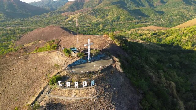 Mount Tapyas landmark in Coron shows the hilltop cross large hillside letters walking paths and surrounding green mountains in warm daylight