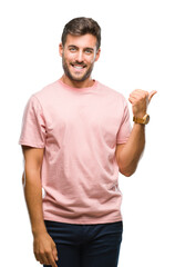 Young handsome man over isolated background smiling with happy face looking and pointing to the side with thumb up.