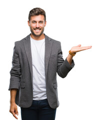 Young handsome business man over isolated background smiling cheerful presenting and pointing with palm of hand looking at the camera.