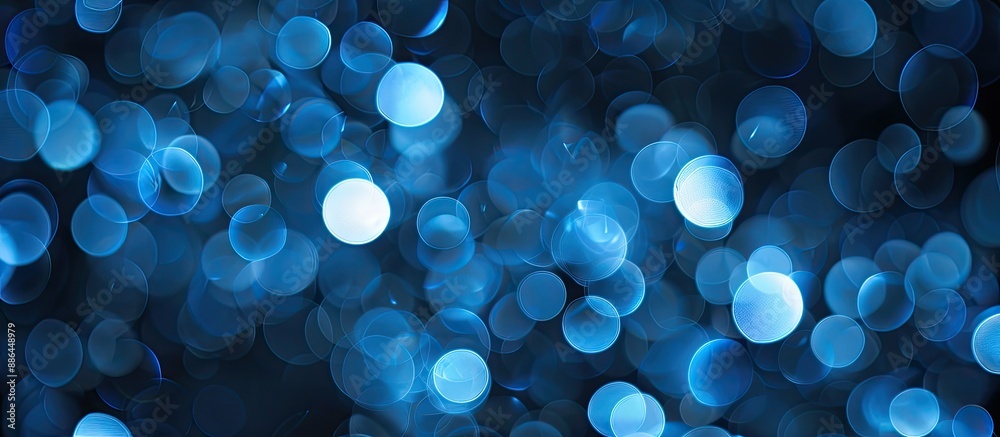 Leinwandbilder A blue blurred bokeh effect against a black backdrop creating shining circles as a wallpaper with an area for text on the image. with copy space image. Place for adding text or design