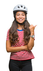 Young arab cyclist woman wearing safety helmet over isolated background smiling with happy face looking and pointing to the side with thumb up.