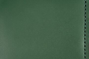 Green leather surface with stitching along the vertical edge on the right and copyspace.