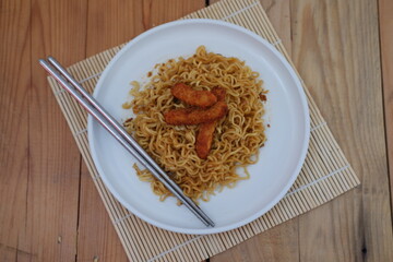 A plate of noodles topped with nugget, creating a delicious and colorful meal.