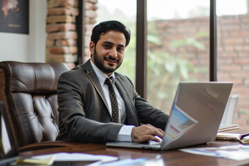 Fototapeta premium Successful Pakistani Man with Laptop, Smiling in Office