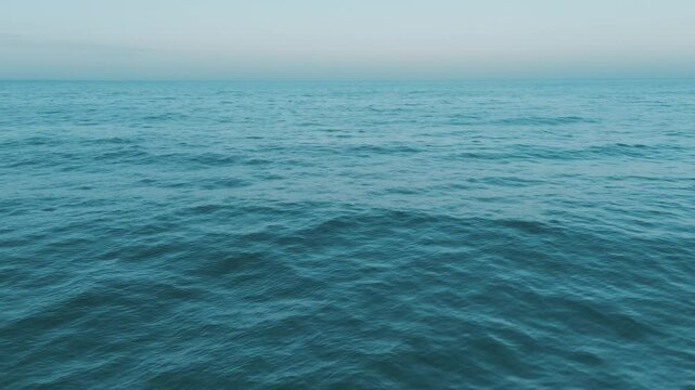 A serene view of tranquil blue ocean waves under a clear sky at sunset, creating a peaceful scene in nature