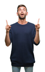 Fototapeta premium Young handsome man wearing winter sweater over isolated background amazed and surprised looking up and pointing with fingers and raised arms.