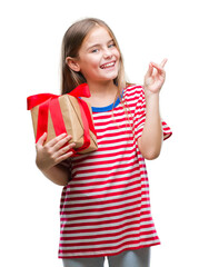 Young beautiful girl giving christmas or valentine gift over isolated background very happy pointing with hand and finger to the side