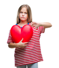 Young beautiful girl holding red heart over isolated background with angry face, negative sign showing dislike with thumbs down, rejection concept