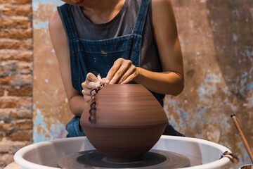 Anonymous woman in an apron creates a handmade ceramic bowl from clay. Creative workshop. The concept of skill and entrepreneurship.