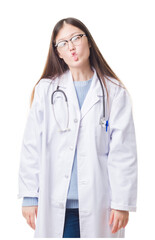 Fototapeta premium Young Chinese doctor woman over isolated background making fish face with lips, crazy and comical gesture. Funny expression.