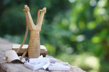 Obraz premium Handmade wooden slingshot, a Y-shaped stick with elastic between the arms; used to propel small stones Thai traditional weapon that use to shoot birds, fish , for fight game or other purposes. 