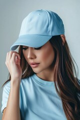 Naklejka premium Serene Young Woman Wearing Blue Cap and T-Shirt on Neutral Background