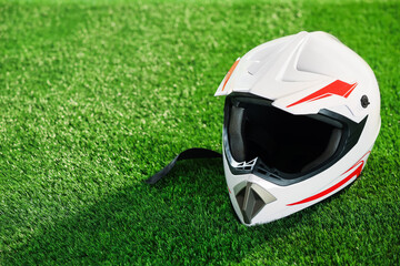 Modern motorcycle helmet with visor on green grass, space for text