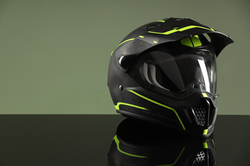 Modern motorcycle helmet with visor on mirror surface against light green background. Space for text
