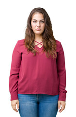 Fototapeta premium Beautiful plus size young woman over isolated background with serious expression on face. Simple and natural looking at the camera.