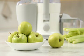Modern juicer, celery and apples on white marble table in kitchen, selective focus