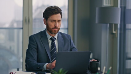 Fototapeta premium Serious businessman texting laptop making coffee sip panoramic workplace closeup