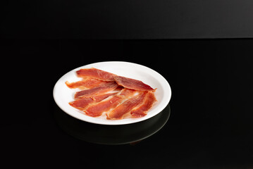 portion smoked meat spanish traditional food jamon Ham on a white plate
