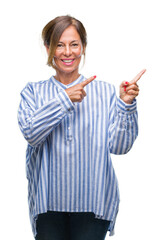 Middle age senior hispanic woman over isolated background smiling and looking at the camera pointing with two hands and fingers to the side.