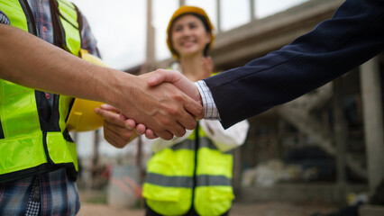 Civil engineer or construction manager with businessman shaking hands at construction site. Building,  and real estate business.