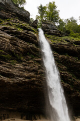 Obraz premium Perichnik waterfall is a beautiful drop from the mountain cliff, in Triglav National Park. Slovenian waterfall. Long for walking and trekking, enter inside the cave to admire it. Power and majesty.