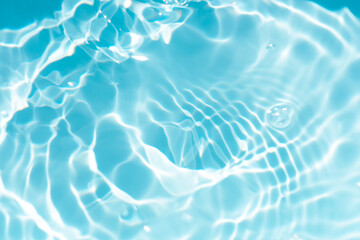 Blue water with ripples on the surface. Defocus blurred transparent blue colored clear calm water surface texture with splashes and bubbles. Water waves with shining pattern texture background.