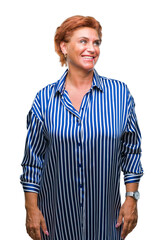 Atrractive senior caucasian redhead woman over isolated background looking away to side with smile on face, natural expression. Laughing confident.
