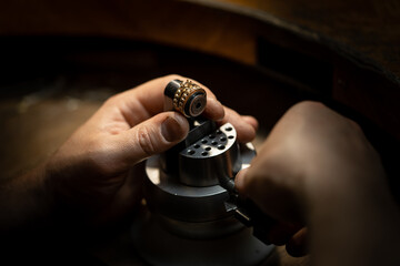 Jeweler puts diamond to golden wedding luxury ring.