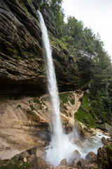 Obraz premium Perichnik waterfall is a beautiful drop from the mountain cliff, in Triglav National Park. Slovenian waterfall. Long for walking and trekking, enter inside the cave to admire it. Power and majesty.