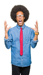 Young african american business man with afro hair wearing glasses and red tie crazy and mad shouting and yelling with aggressive expression and arms raised. Frustration concept.