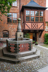 Fototapeta premium Fountain in the courtyard of the longhouse of the Holy Spirit Church in Wismar