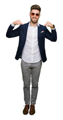 Young handsome elegant man wearing sunglasses and fashion blazer looking confident with smile on face, pointing oneself with fingers proud and happy.