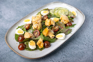Warm salad with rapan (snails), tomatoes, cucumbers, leafy vegetables, quail eggs and olive oil. Traditional seafood salad. Close-up, selective focus.