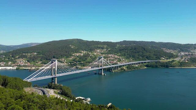 Aerial drone point of view of Vigo. View of Rande Bridge and Vigo Ria. Mussels farming structures aligned in the middle of the water. Beautiful Galician green landscape. Drone panning right. 
