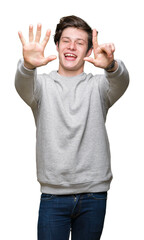 Fototapeta premium Young handsome sporty man wearing sweatshirt over isolated background showing and pointing up with fingers number seven while smiling confident and happy.