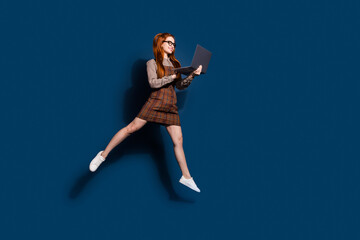 Obraz premium Full length photo of pretty excited lady dressed plaid outfit jumping chatting modrn device emtpy space isolated dark blue color background