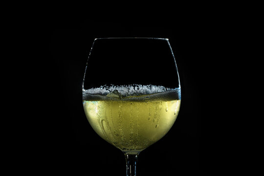 calice di vino bianco, fermo o statico, riempito fino a met&agrave; su sfondo nero