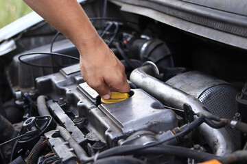 Fototapeta premium Close-up of a diesel engine oil filler cap. The man's hand checks whether the oil filler cap is tightened tightly. Car repair or maintenance concept. The mechanic inspects the car