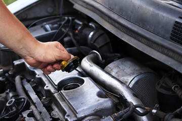 Fototapeta premium Change of oil. A man's hand opens or closes the oil filler cap. Changing the oil in a diesel car engine. Car maintenance. Old car. The mechanic inspects the car